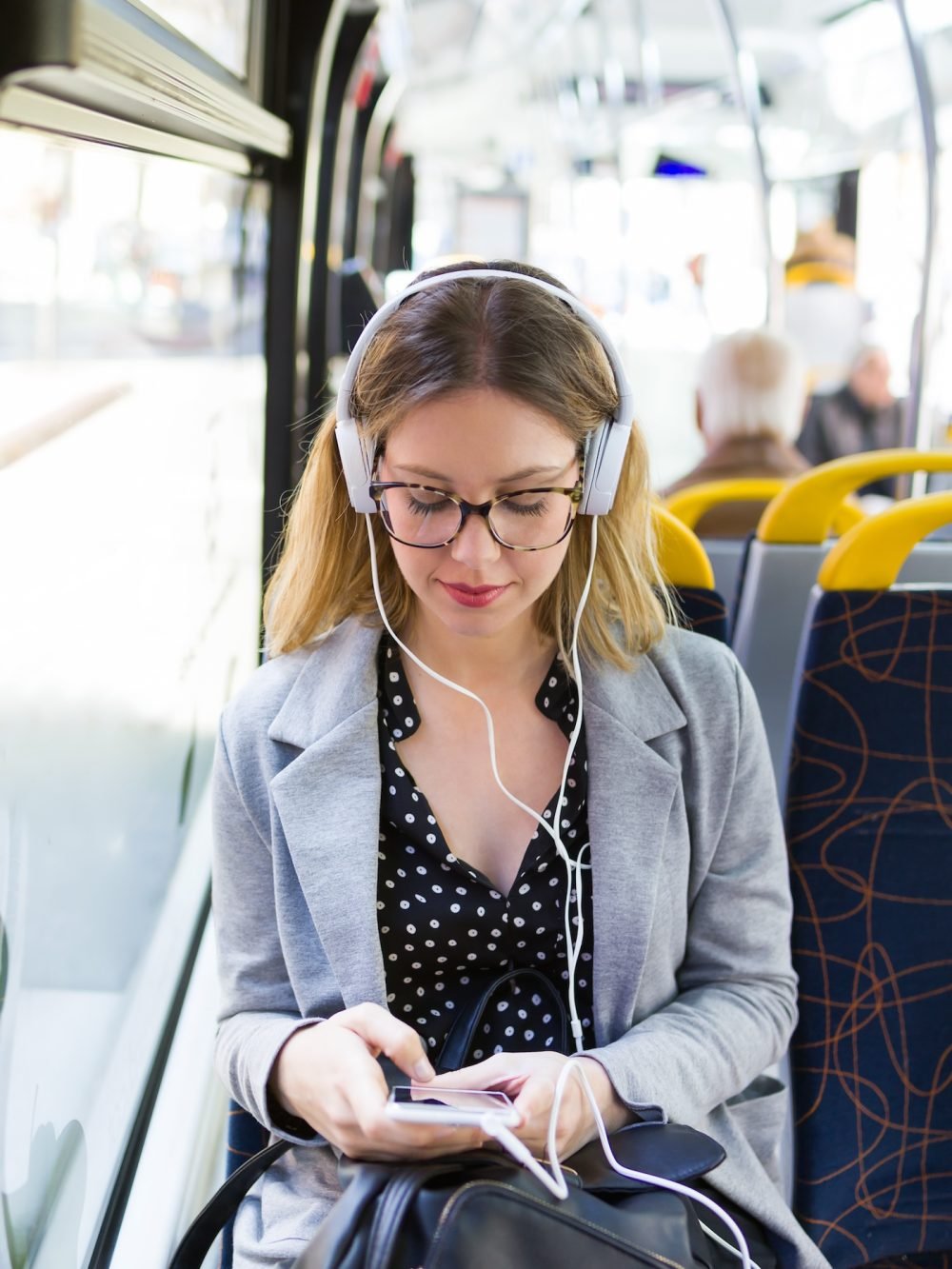 Shot of pretty young woman listening to music with mobile phone at the bus.